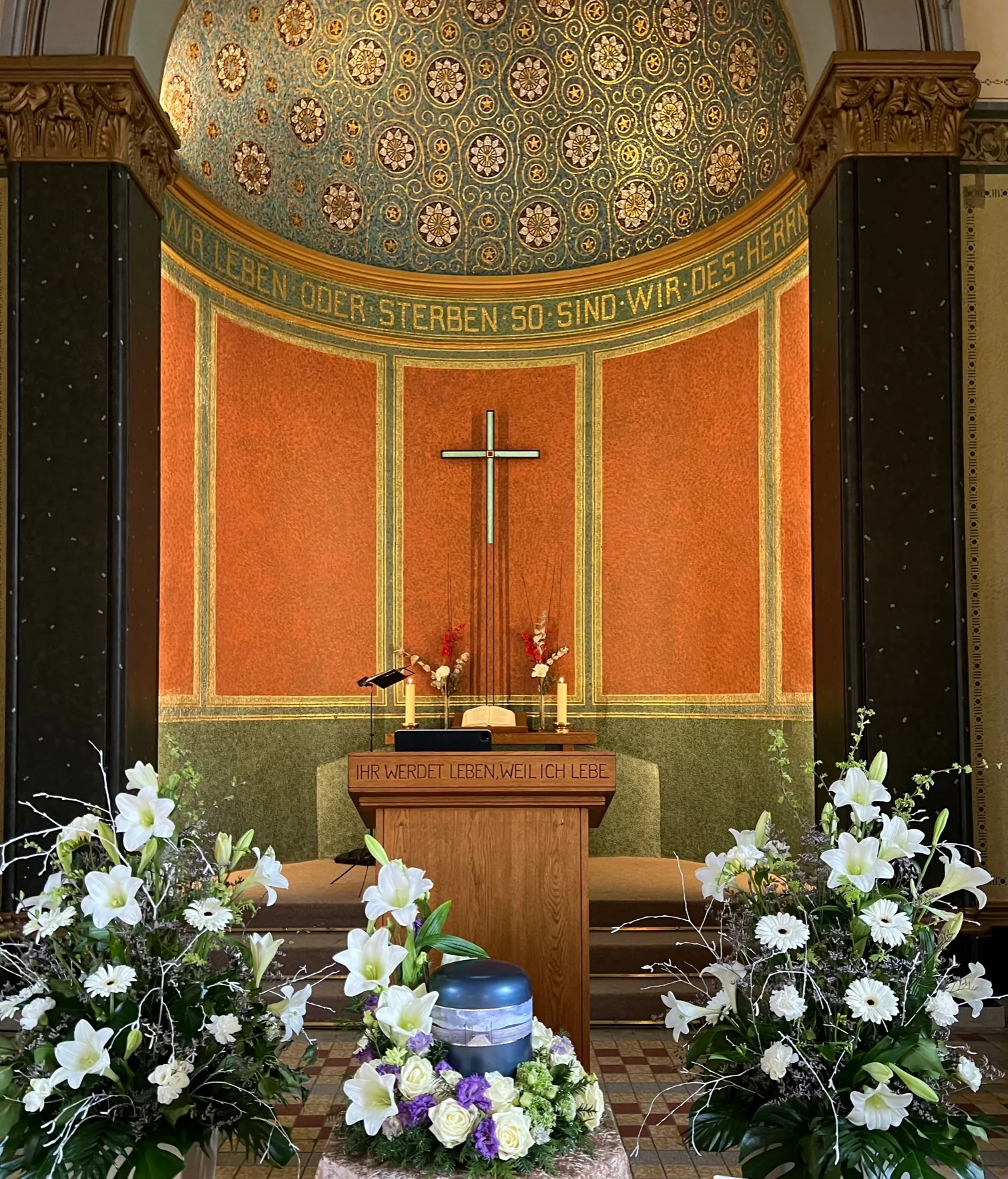 Festlich geschmückte Kapelle mit Urne, weißen Lilien und Kerzen