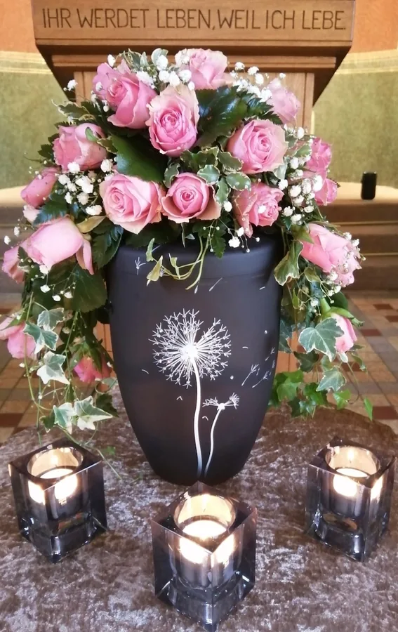 Urne mit Pusteblume, Rosen und Kerzen